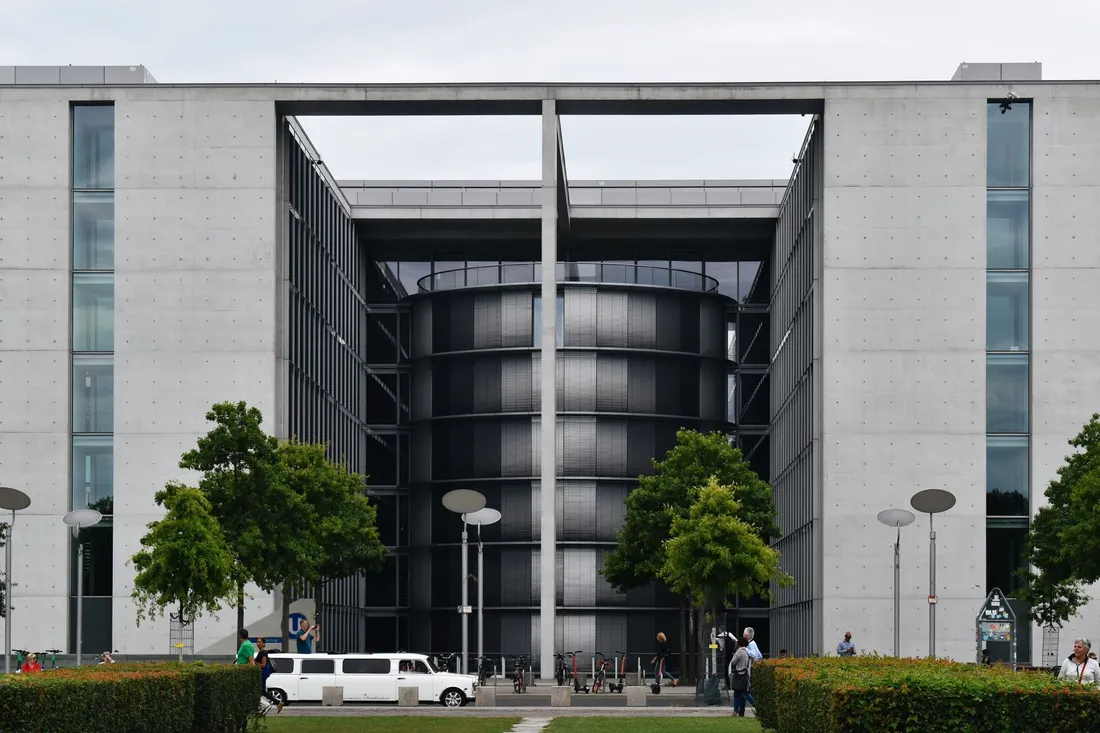Betonfassade des Paul-Löbe-Hauses in Berlin mit Bäumen und Passanten davor