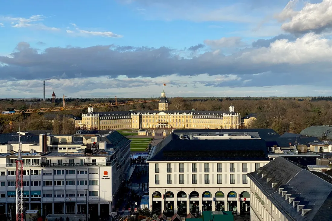 Blick über Innenstadtdächer auf ein gelbes Barockschloss mit Mittelturm