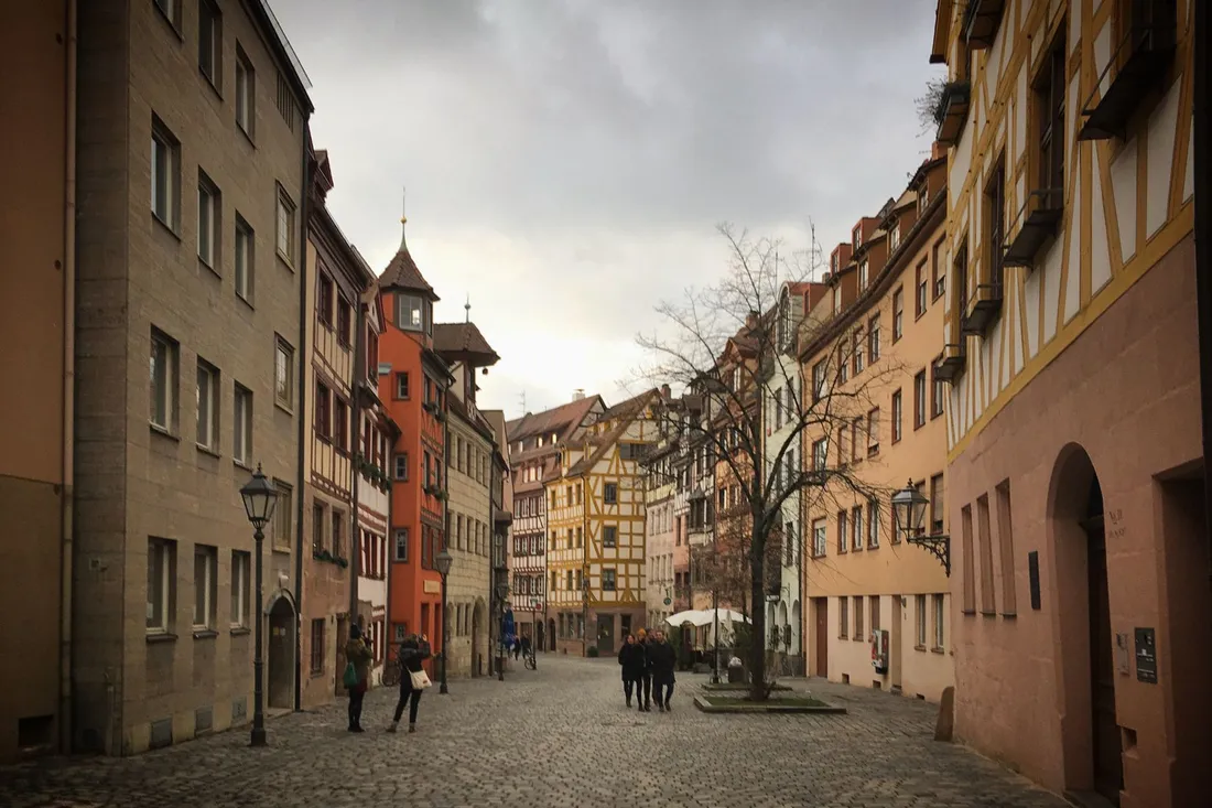 Kopfsteingepflasterte Altstadtgasse mit bunten Fachwerkhäusern bei bedecktem Himmel