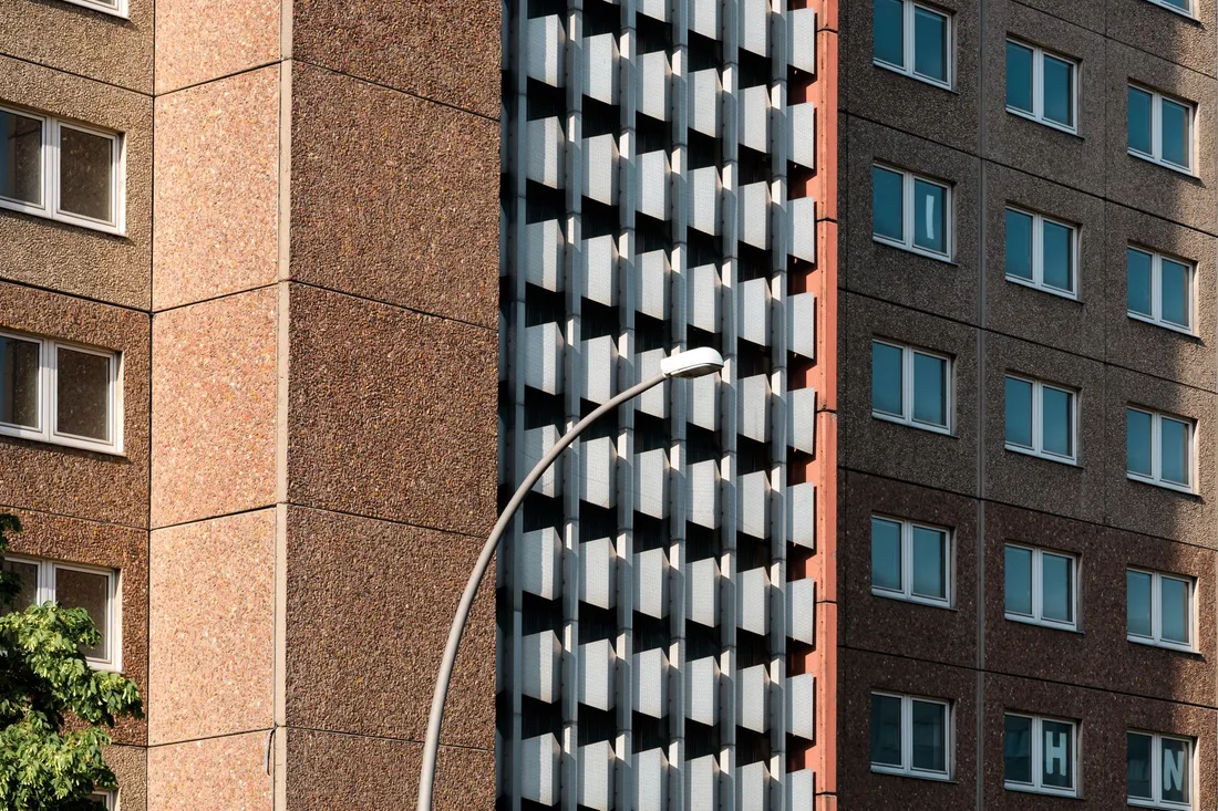 Waschbetonfassade eines Hochhauses mit Fensterreihen und geschwungener Straßenlaterne