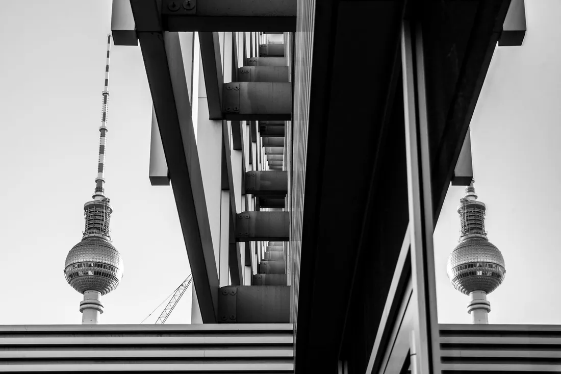 Schwarzweiß fotografierte Fernsehturmkugel und ihre Spiegelung zwischen Stahlträgern